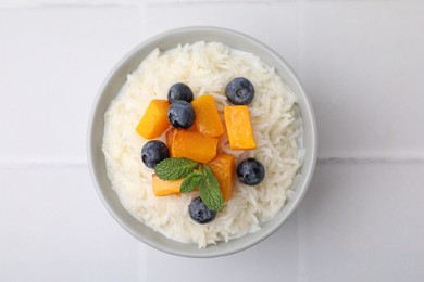 Photo of Bowl of delicious rice porridge with blueberries and pumpkin on white table, top view