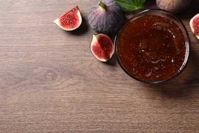 Glass bowl with tasty sweet jam and fresh figs on wooden table, flat lay. Space for text