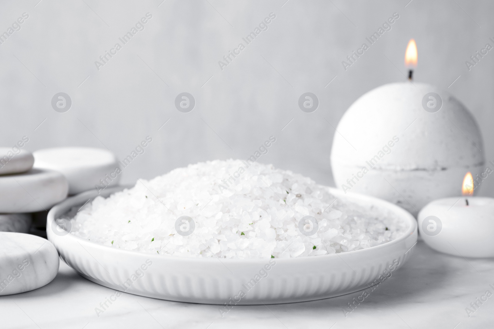 Photo of White sea salt for spa scrubbing procedure on marble table against grey background