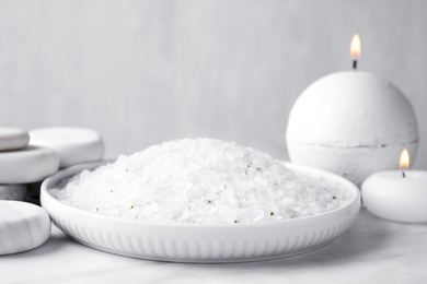 Photo of White sea salt for spa scrubbing procedure on marble table against grey background