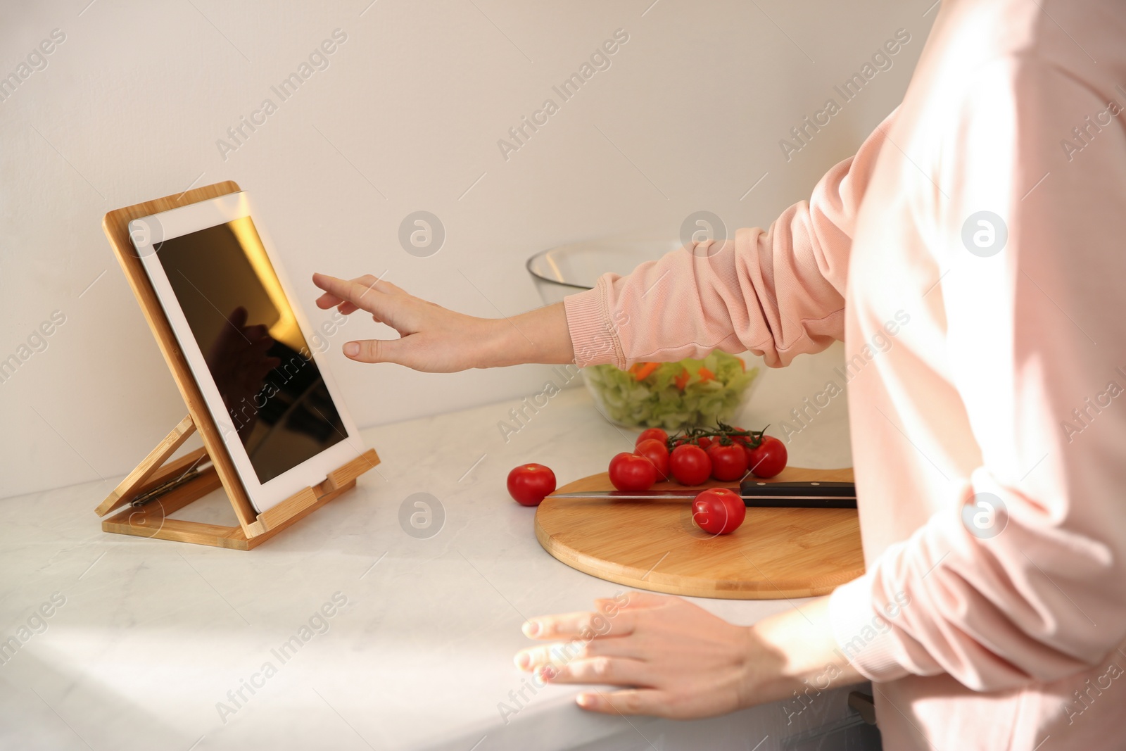 Photo of Young woman with tablet cooking at counter in kitchen, closeup