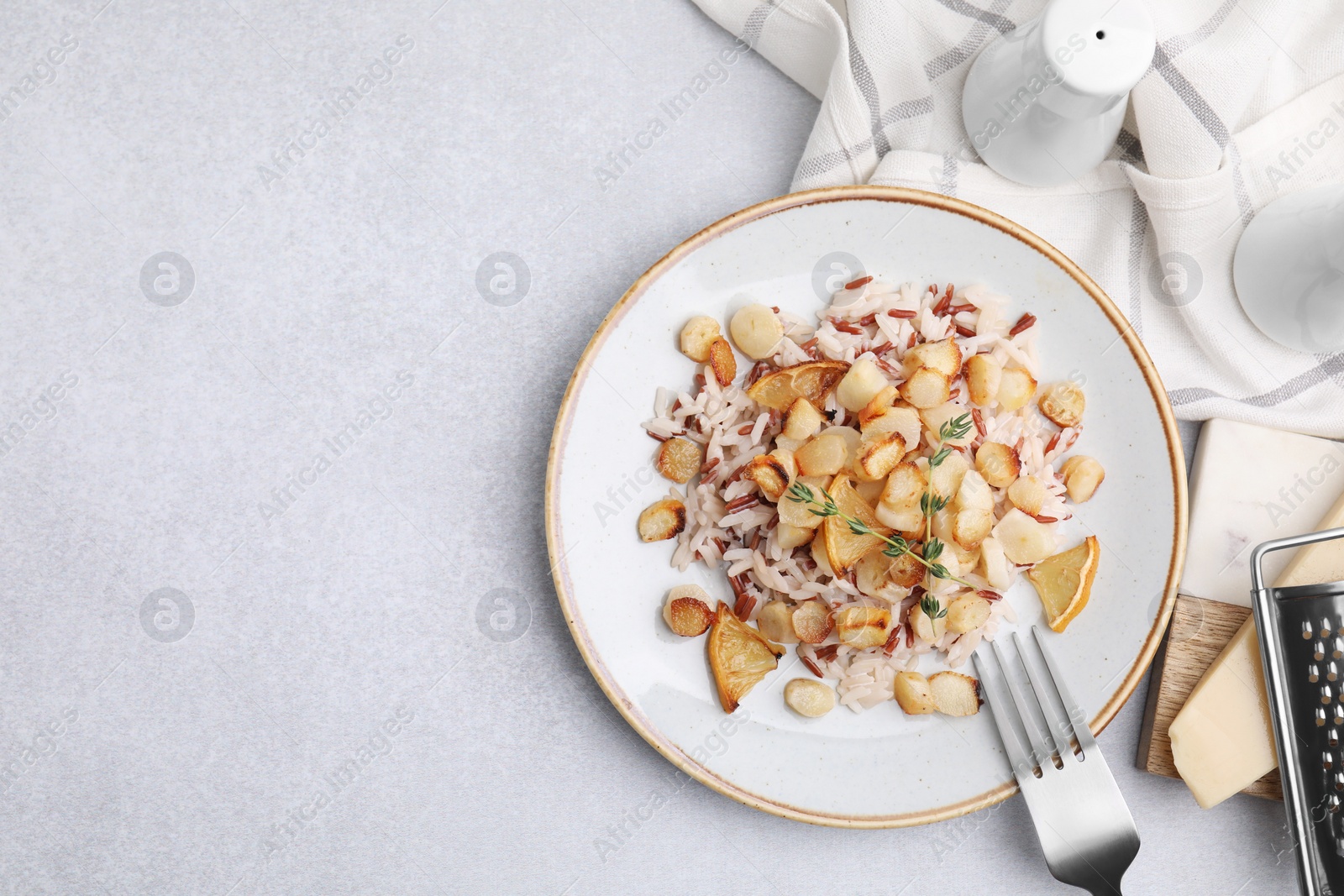 Photo of Plate with baked salsify roots, lemon, rice and fork on light grey table, flat lay. Space for text