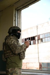 Photo of Military mission. Soldier in uniform with drone controller inside abandoned building