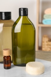 Photo of Solid shampoo bar and bottles of cosmetic product on wooden table in bathroom, closeup
