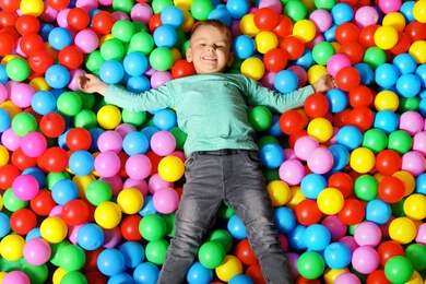 Cute child playing in ball pit indoors