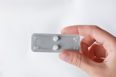 Photo of Woman holding blister of emergency contraception pills against blurred background, closeup