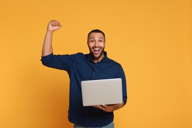 Photo of Happy young man with laptop on yellow background