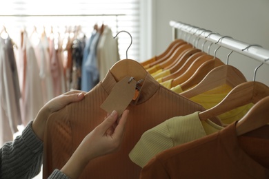 Photo of Woman looking at price tag in modern clothing boutique, closeup