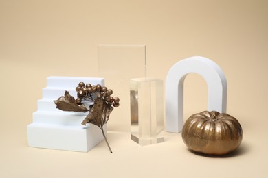 Photo of Autumn presentation for product. Geometric figures, golden pumpkin and branch with berries on beige background