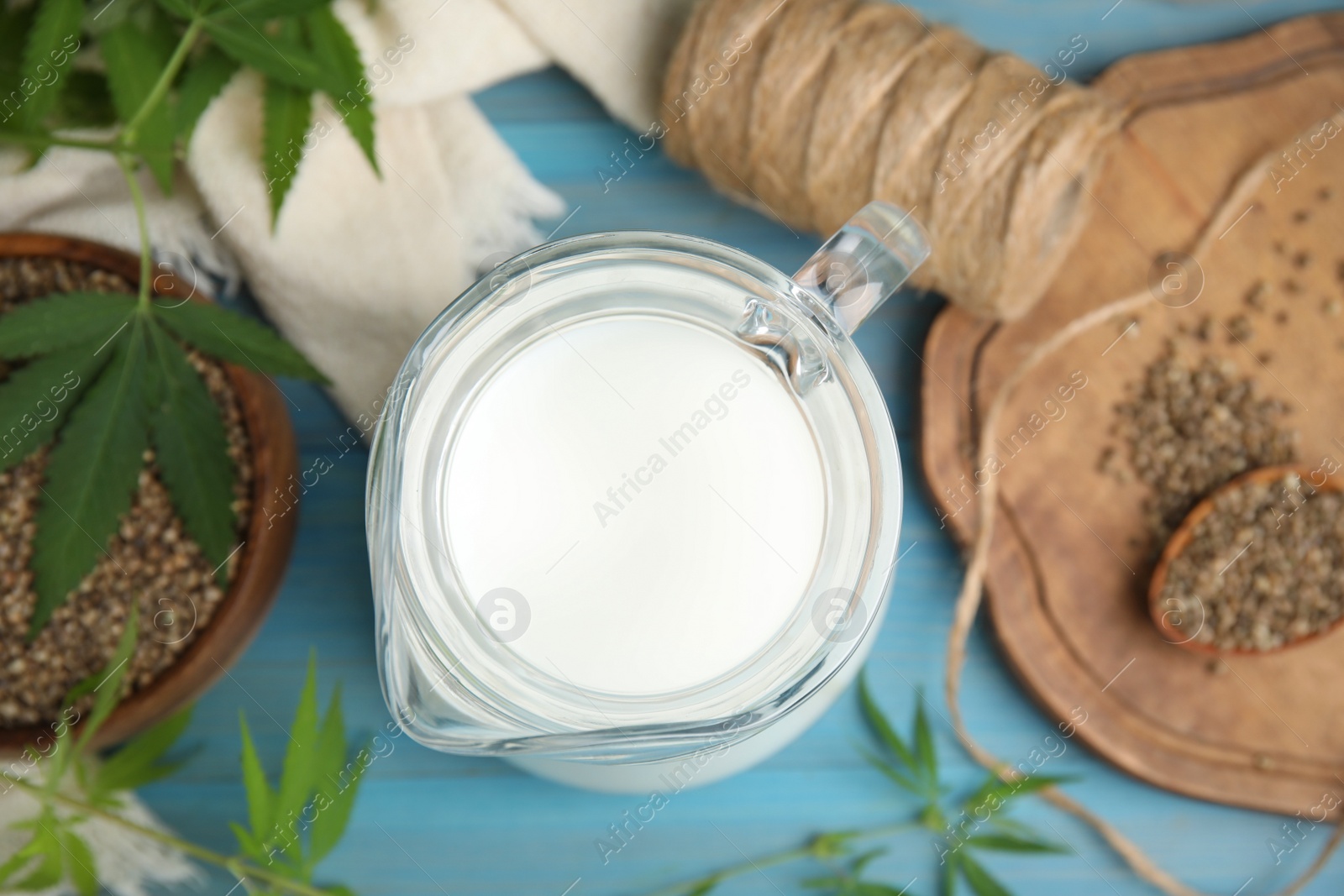 Photo of Pitcher of hemp milk on light blue wooden background, top view