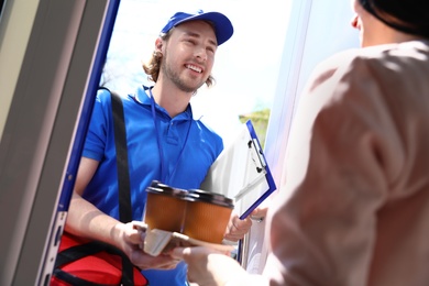 Photo of Woman receiving order from courier at door. Food delivery service