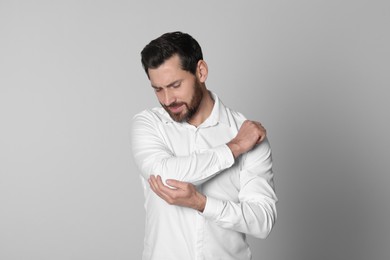 Photo of Man suffering from pain in his elbow on light background. Arthritis symptoms