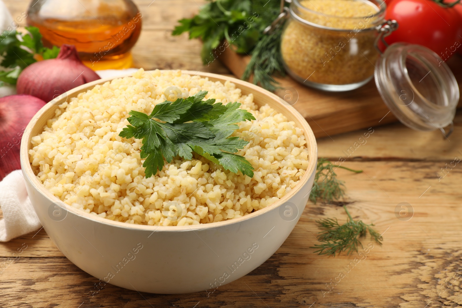 Photo of Delicious bulgur with parsley on wooden table, closeup