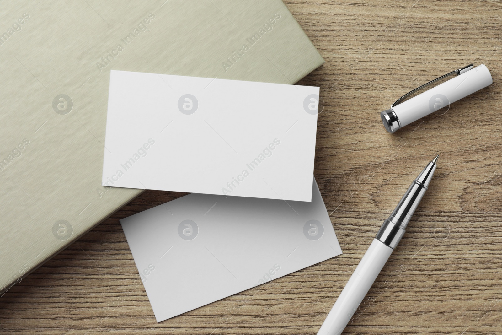 Photo of Blank business cards, notebook and pen on wooden table, flat lay. Mockup for design