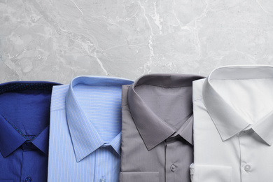 Stylish shirts on grey marble table, flat lay with space for text. Dry-cleaning service