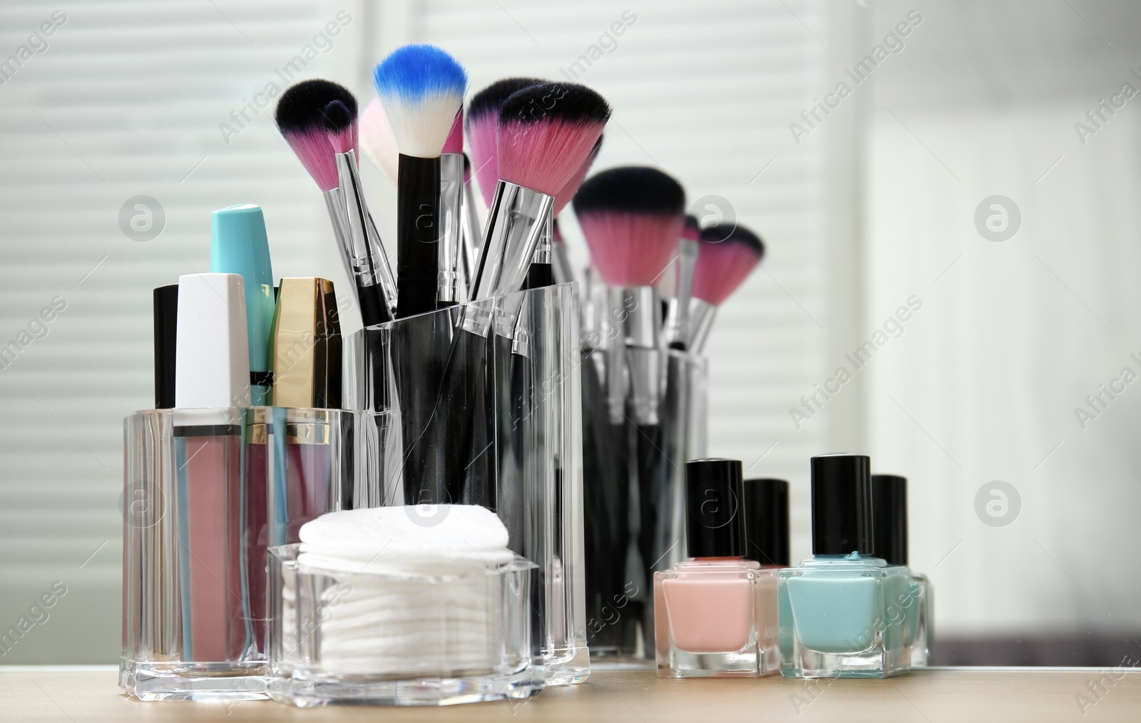 Photo of Organizer with makeup cosmetic products on table near mirror