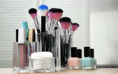 Organizer with makeup cosmetic products on table near mirror