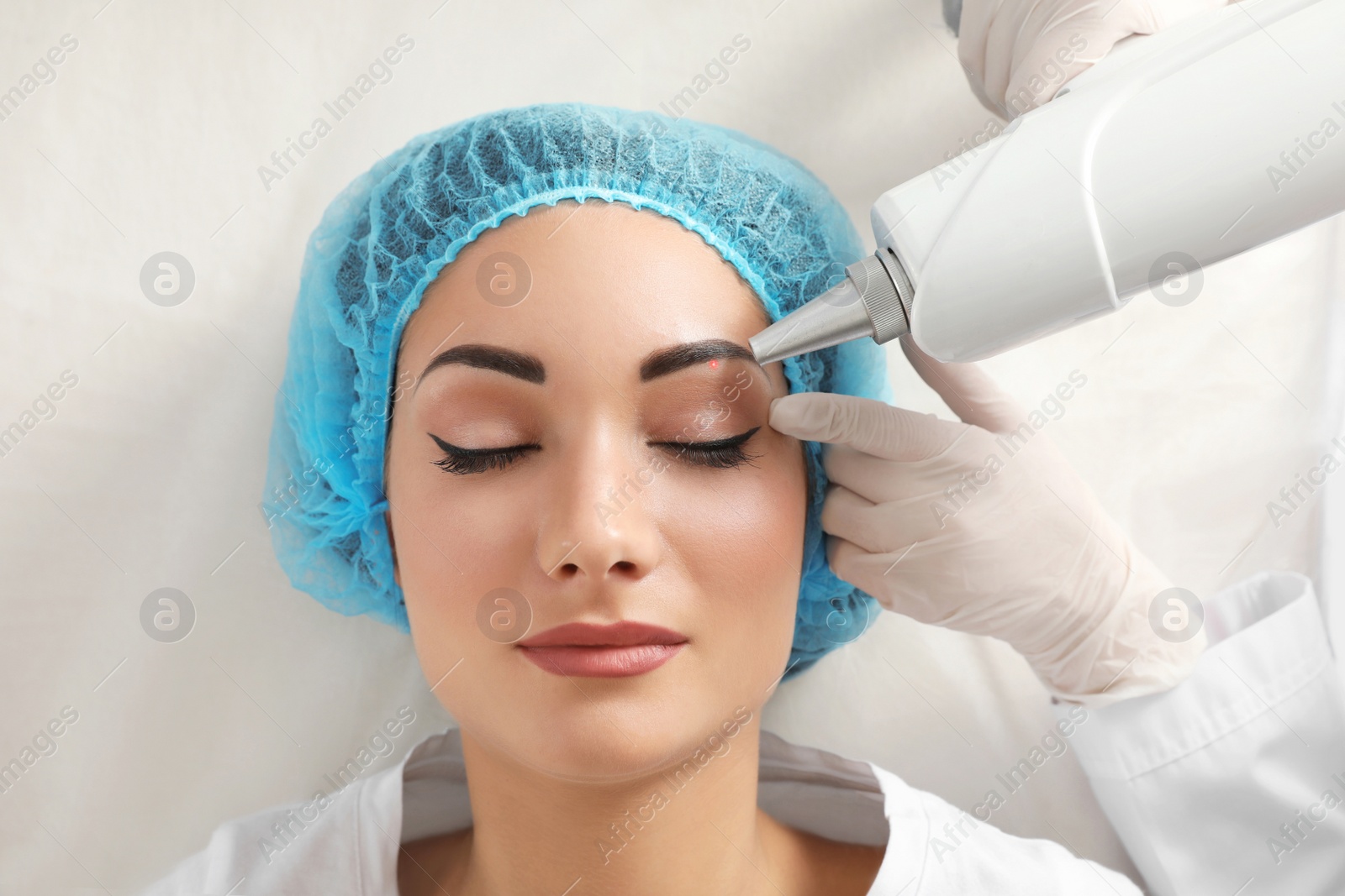 Photo of Woman undergoing laser tattoo removal procedure in salon, closeup