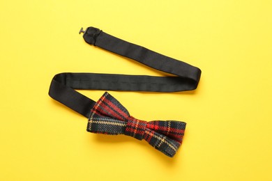 Photo of Stylish tartan bow tie on yellow background, top view