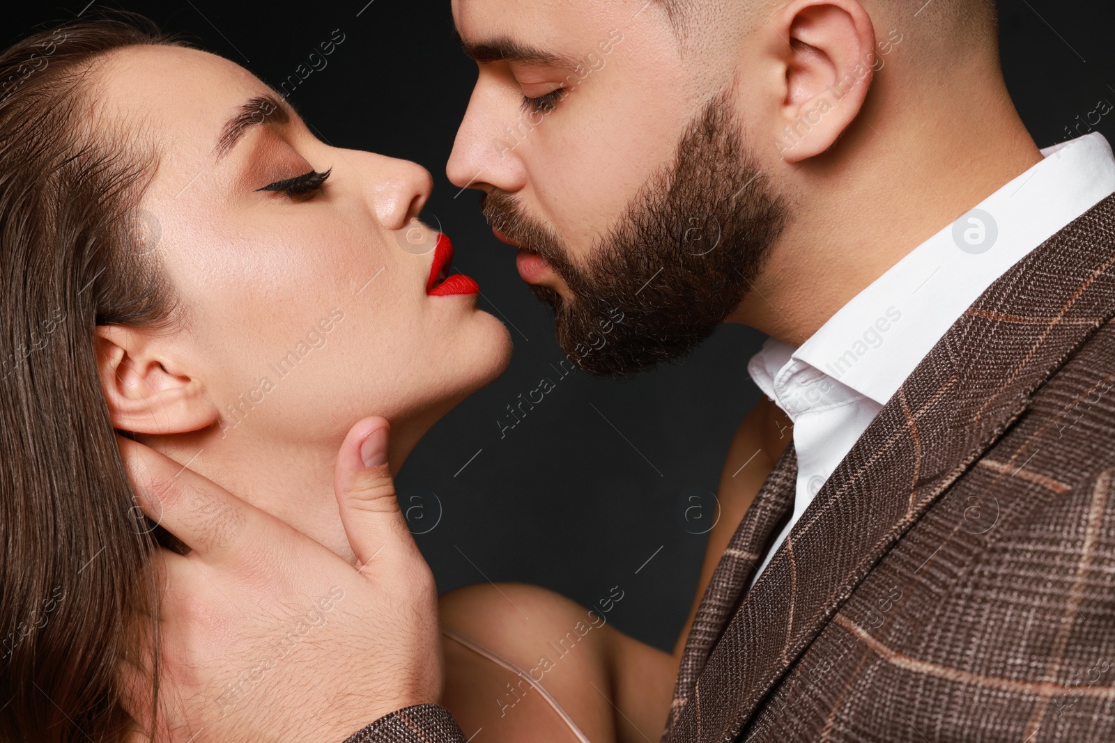 Photo of Handsome bearded man with sexy lady on dark background, closeup