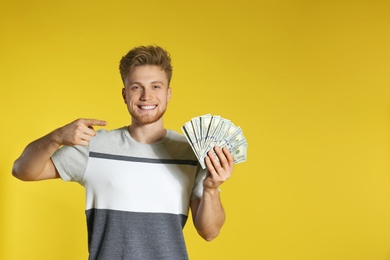 Young man with money on color background. Space for text