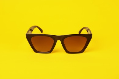 Stylish pair of sunglasses on yellow background