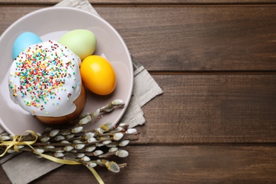 Traditional Easter cake, pussy willows and colorful eggs on wooden table, top view. Space for text