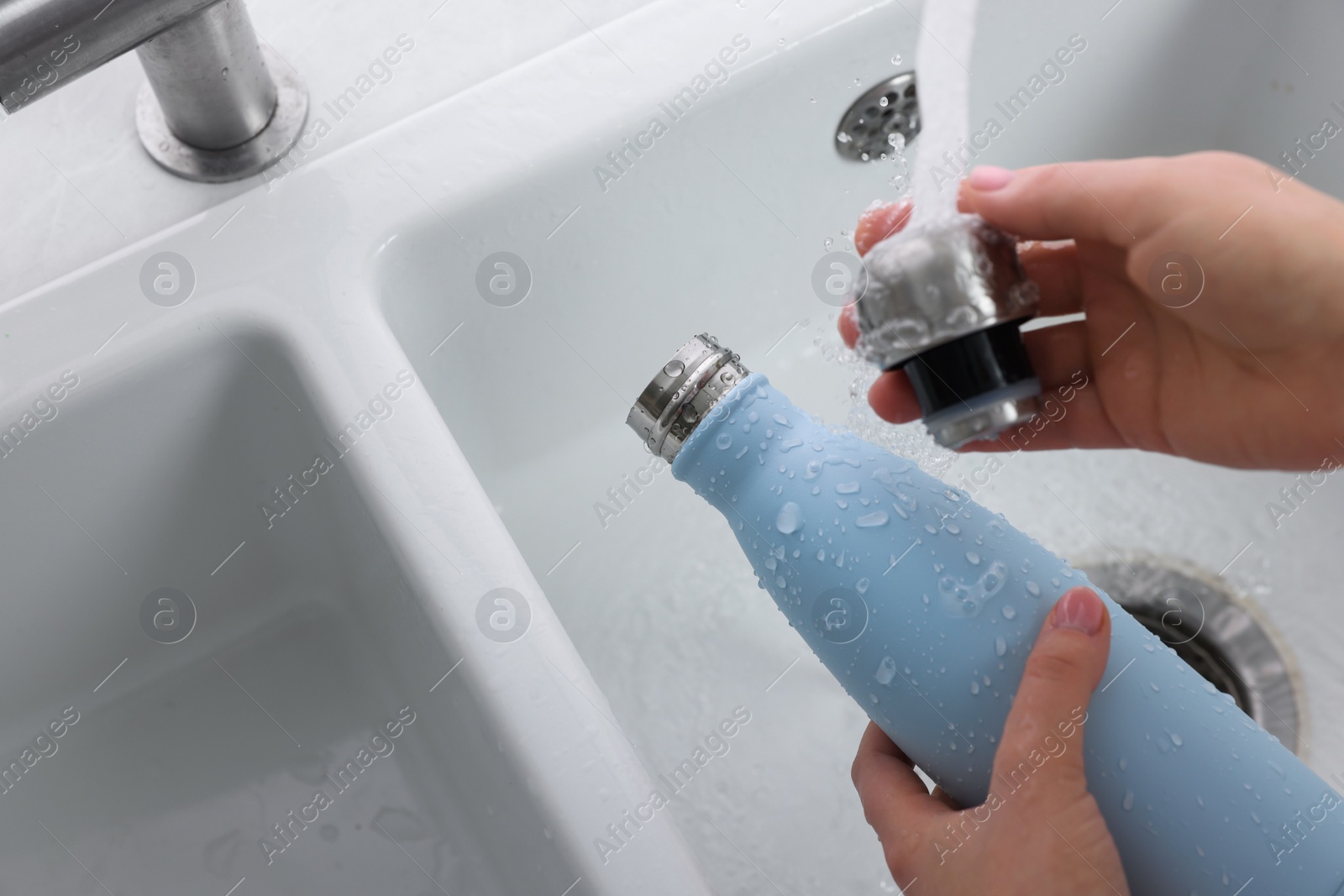 Photo of Woman washing thermo bottle in kitchen, above view