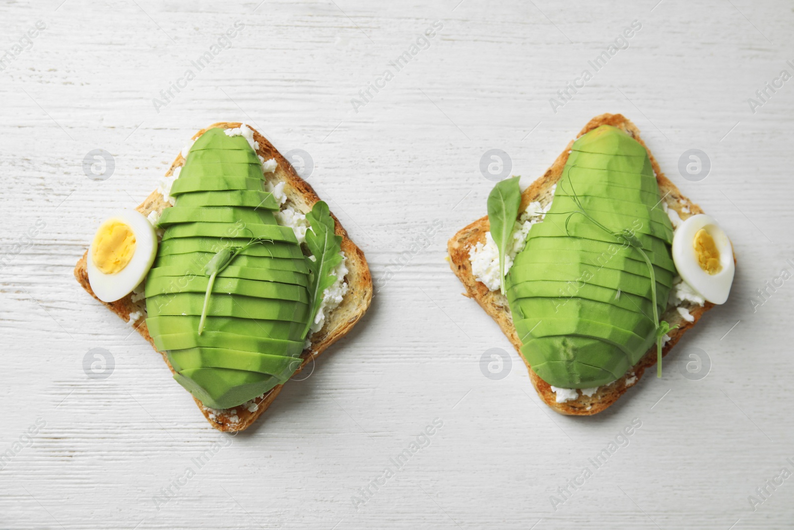 Photo of Avocado toasts on white wooden table, flat lay