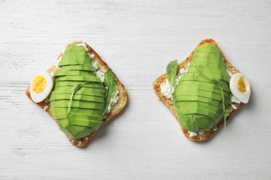 Photo of Avocado toasts on white wooden table, flat lay