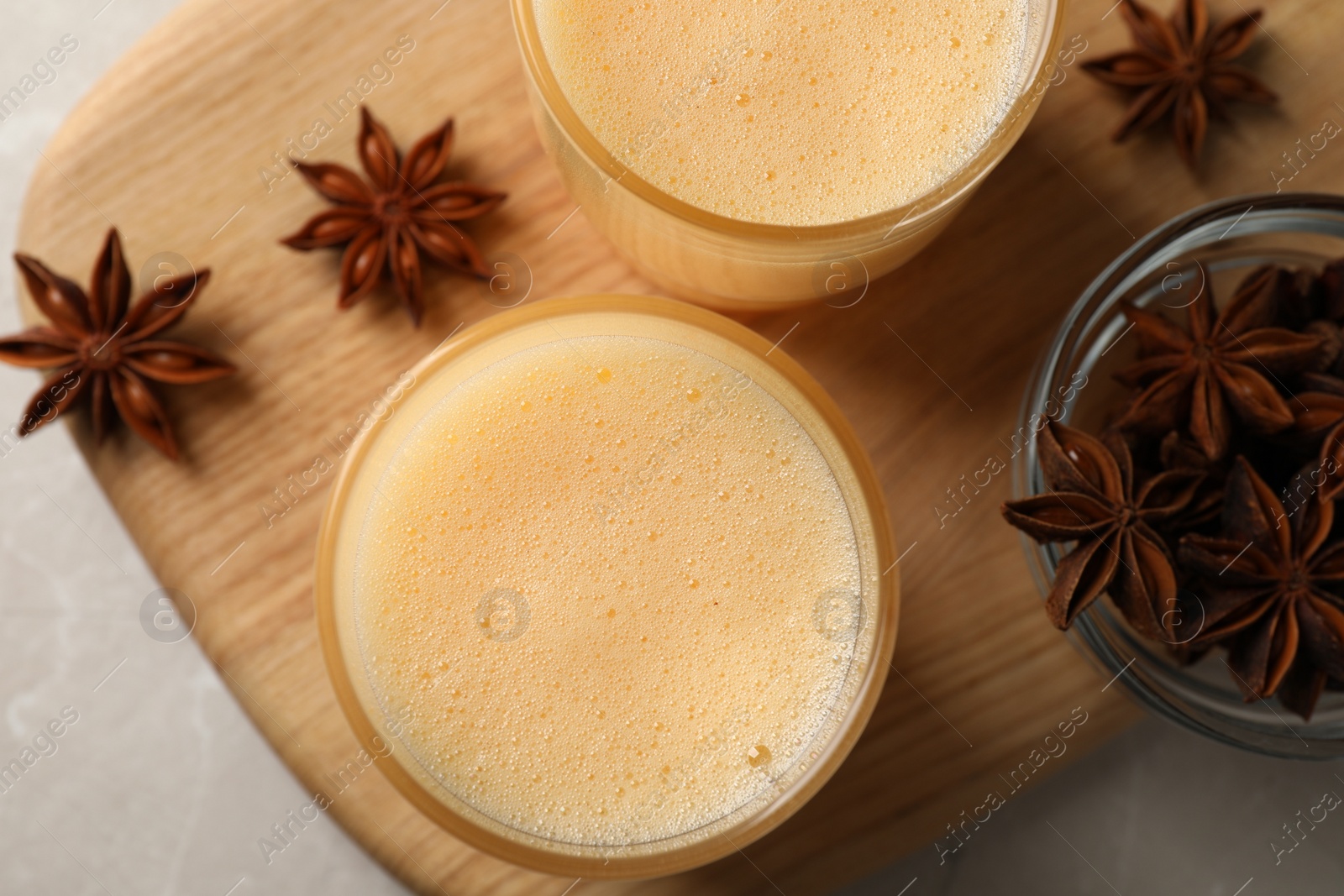 Photo of Glasses of delicious eggnog with anise on grey marble table, top view