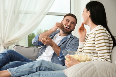 Photo of Happy couple watching movie with popcorn at home