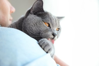 Man with cute cat on blurred background, closeup