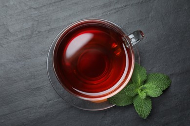 Photo of Cup of hot aromatic tea with mint on black table, flat lay