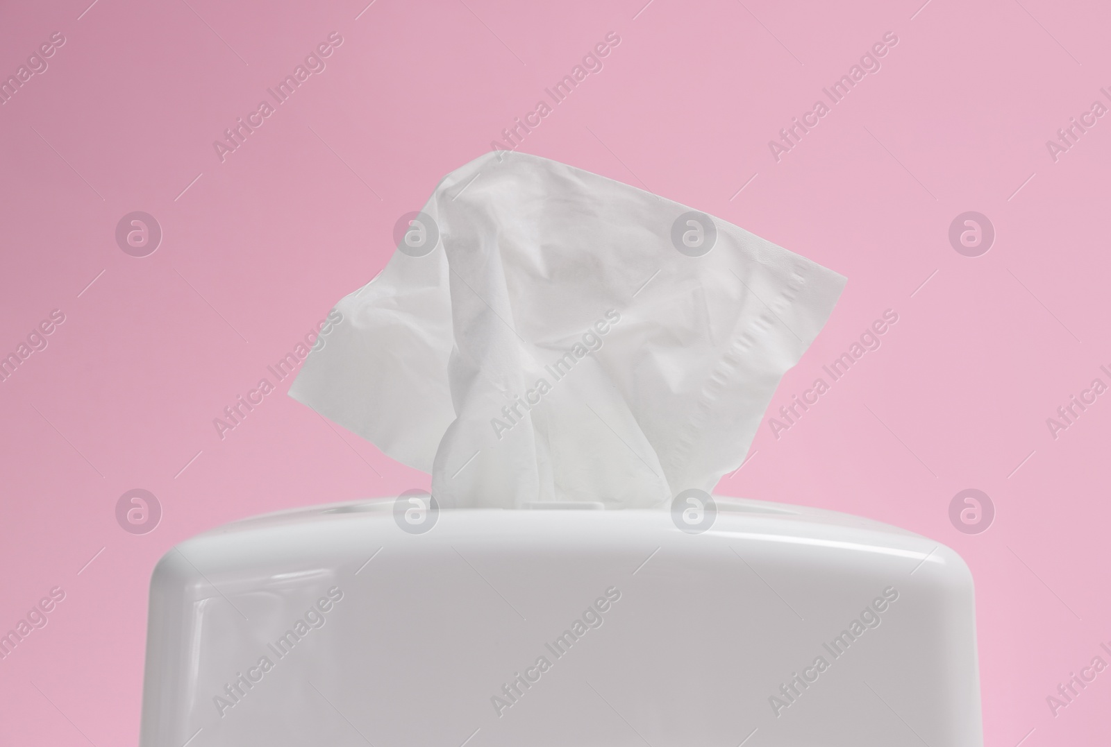 Photo of Holder with paper tissues on pink background, closeup