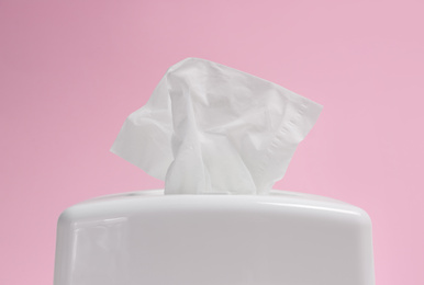 Photo of Holder with paper tissues on pink background, closeup