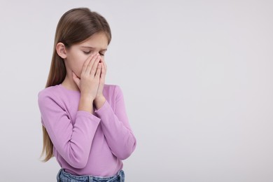 Sick girl coughing on light background, space for text