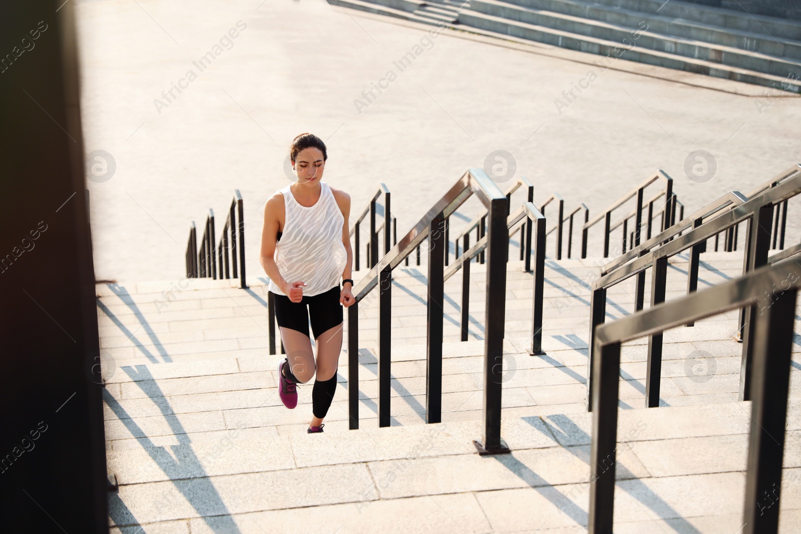 Photo of Sporty young woman running upstairs on sunny day