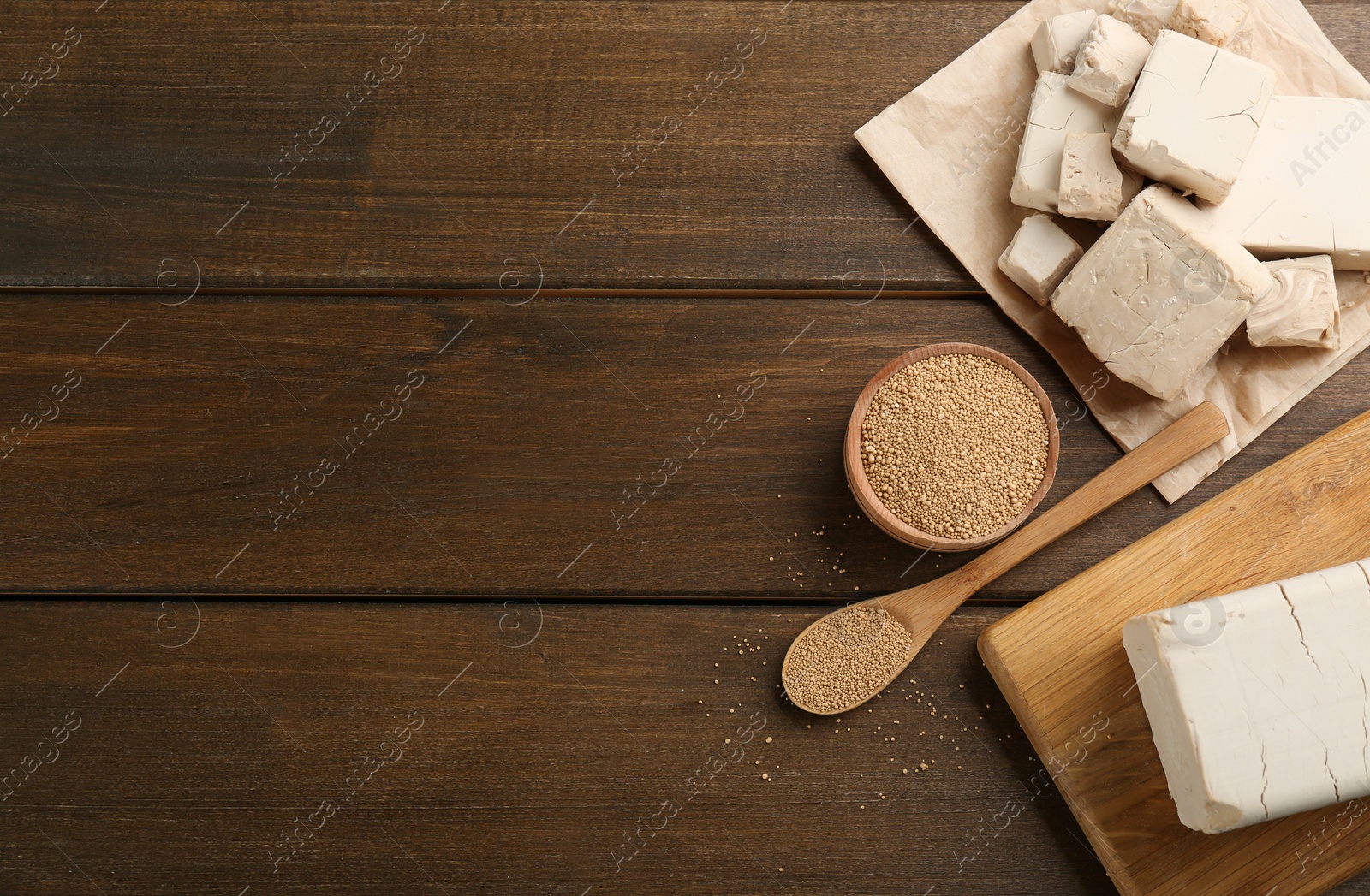 Photo of Compressed and granulated yeast on wooden table, flat lay. Space for text