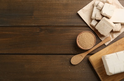 Compressed and granulated yeast on wooden table, flat lay. Space for text