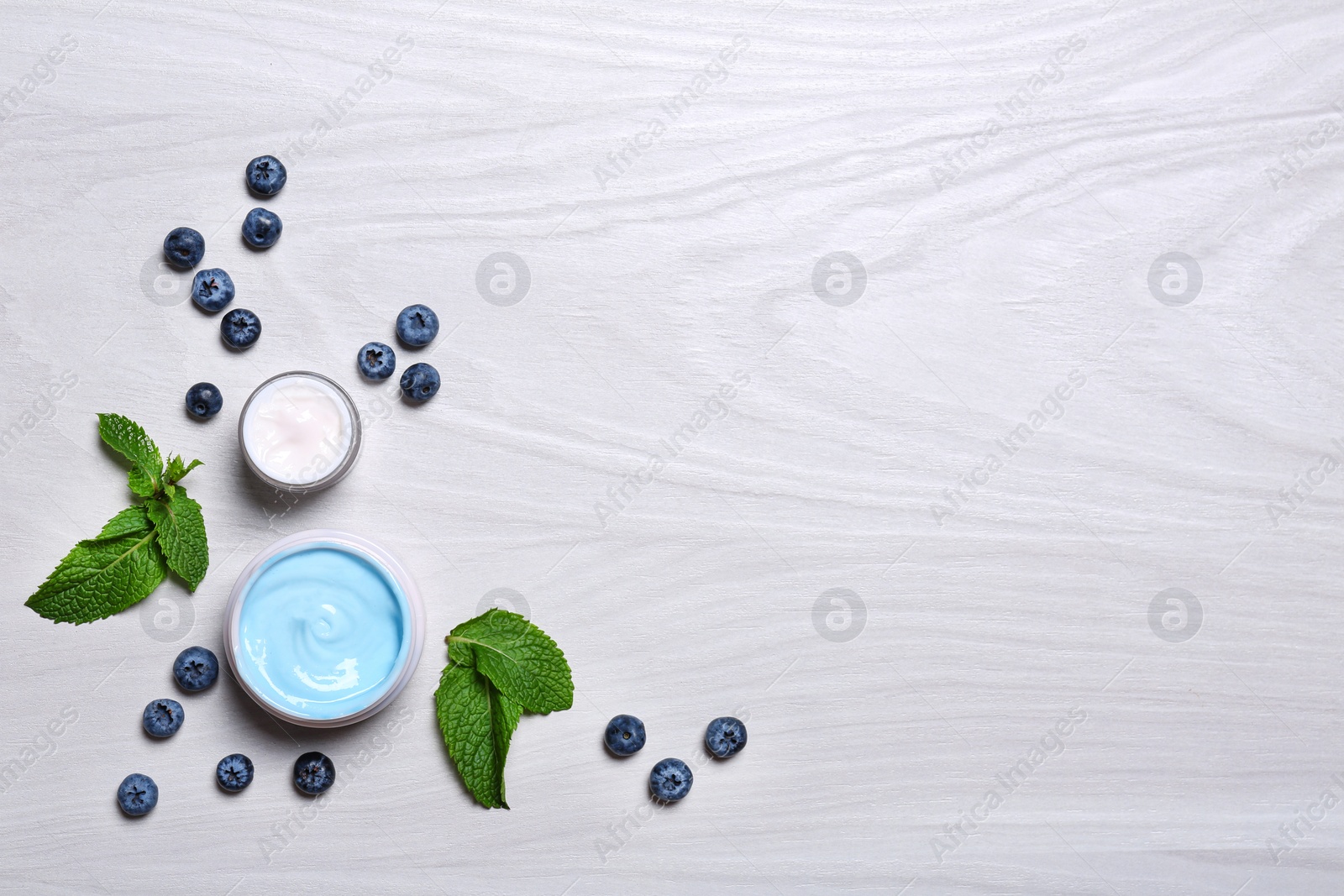 Photo of Flat lay composition with jars of body cream on light wooden background. Space for text