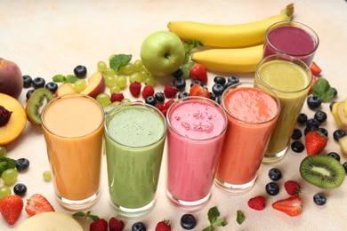 Photo of Fresh colorful fruit smoothies and ingredients on beige table