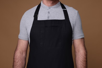 Photo of Man wearing kitchen apron on brown background, closeup. Mockup for design