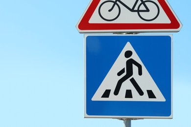 Post with Pedestrian Crossing and No Bikes traffic signs against blue sky on sunny day