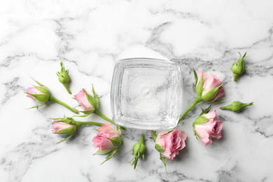 Photo of Flat lay composition with cosmetic gel and beautiful flowers on white marble table