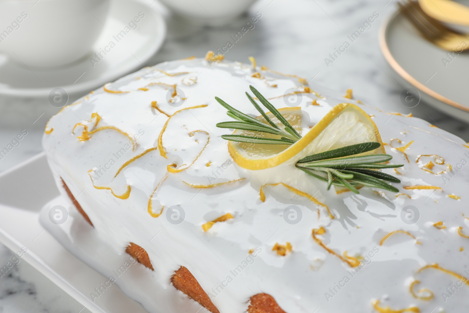 Photo of Tasty lemon cake with glaze and rosemary on table, closeup