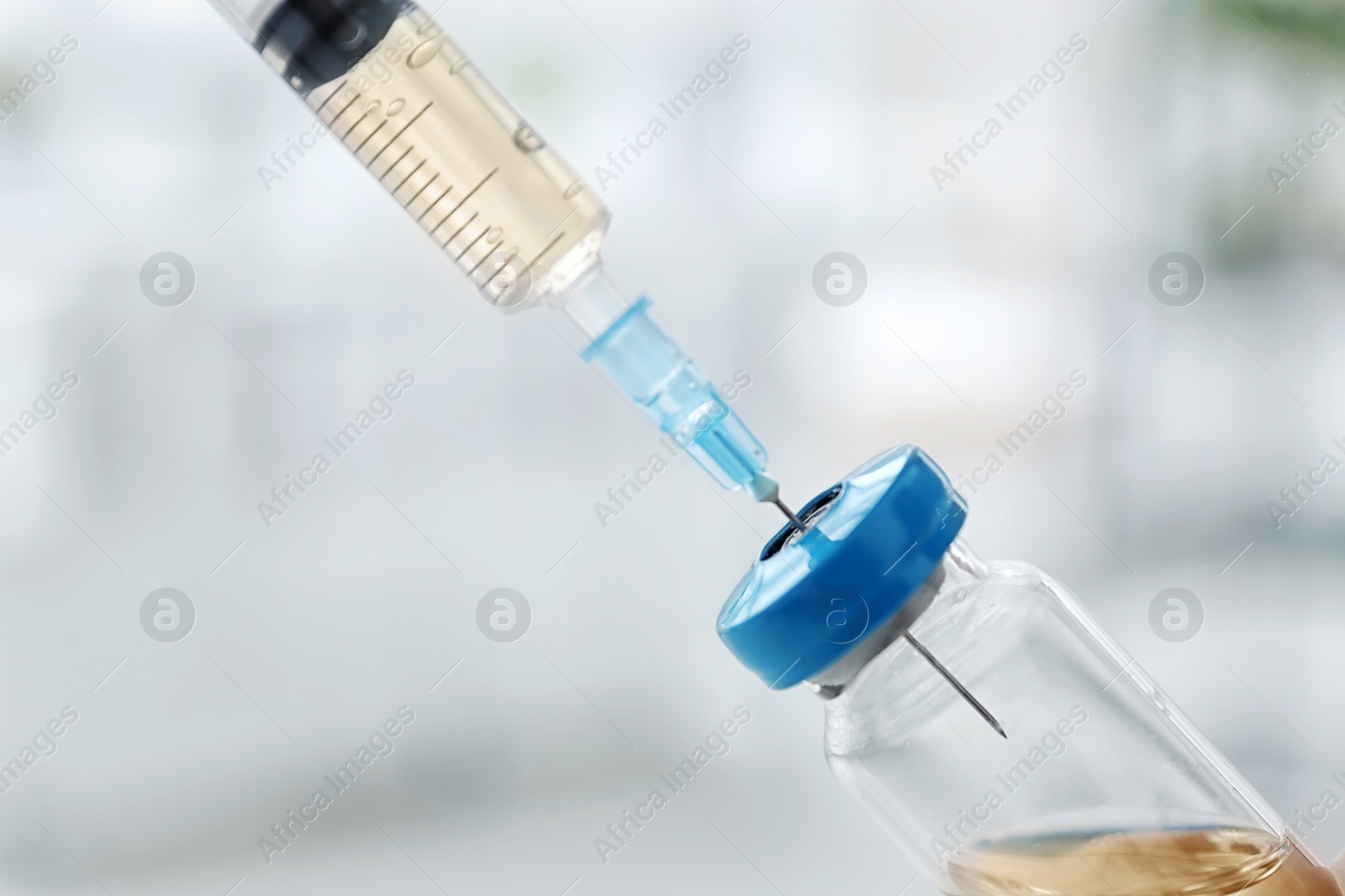 Photo of Vial with vaccine and syringe on blurred background