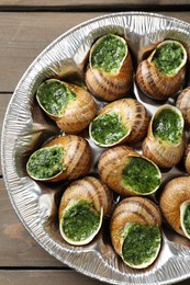 Photo of Delicious cooked snails on wooden table, top view