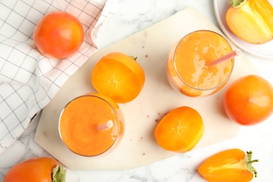 Photo of Tasty persimmon smoothie with straws and fresh fruits on white marble table, flat lay