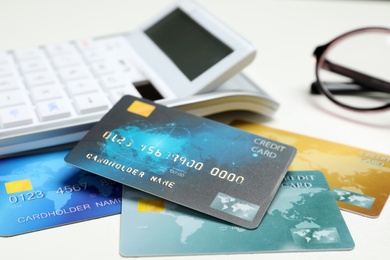 Credit cards and calculator on white table, closeup